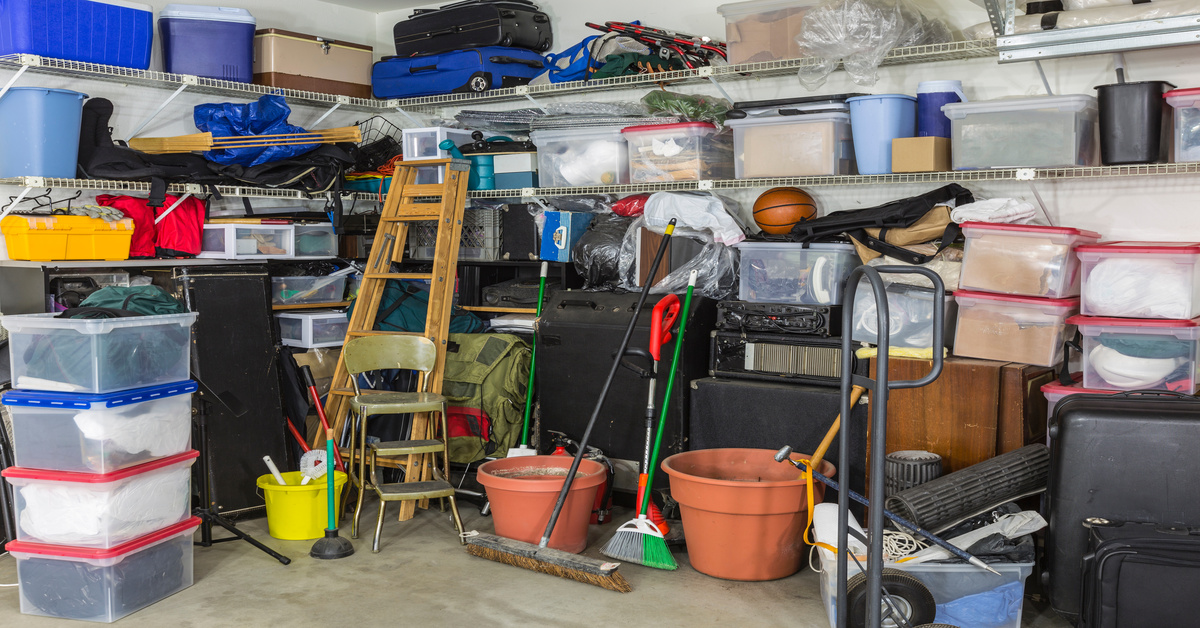 A garage with several wall-mounted shelves. The space is brimming with miscellaneous goods in containers.