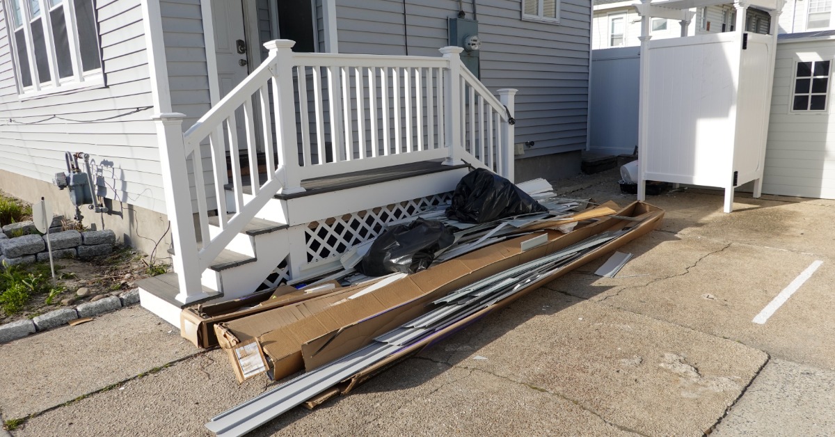 A collection of trash and leftovers from home renovations sitting in the driveway alongside a set of stairs.